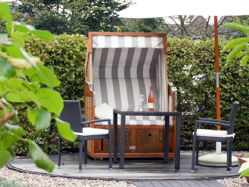 Cozy seating area with a beach chair and garden chairs in a green outdoor setting.