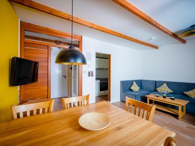 Moderner Ess- und Wohnbereich mit Holzmöbeln und blauer Sofa-Ecke in einem Hotelzimmer.