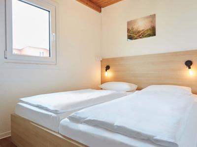 Helles Hotelzimmer mit Doppelbett, Holzdecke und Fenster mit Außensicht.