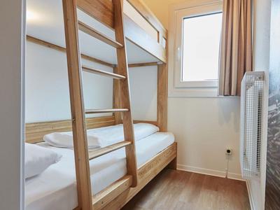 Schlichtes Schlafzimmer mit Holz-Etagenbett, Fenster und hellem Holzboden.