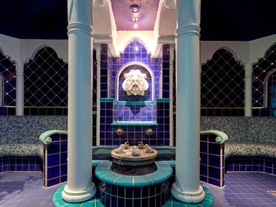 Luxuriöser Hammam mit blauen Fliesen, Säulen und zentralem Brunnen