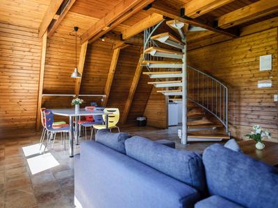 Gemütlicher Wohnbereich mit Holzverkleidung, blauem Sofa und Esstisch neben Wendeltreppe.
