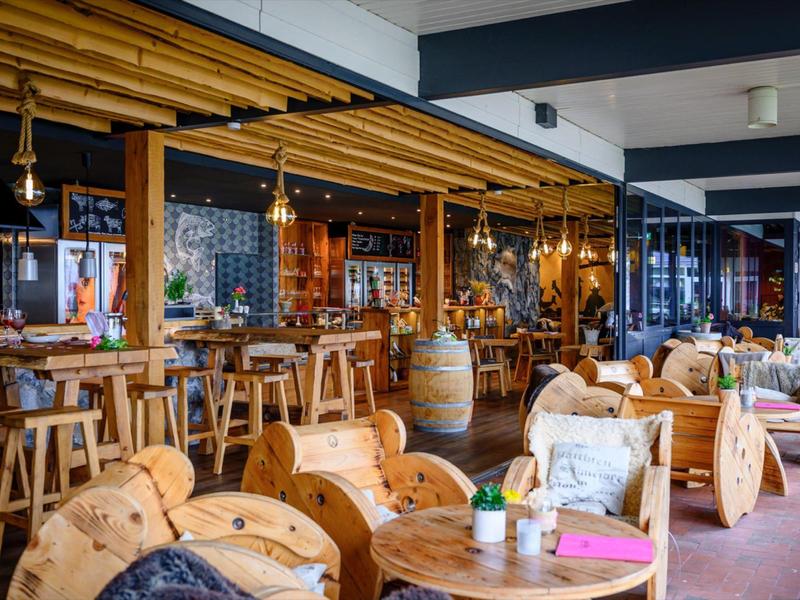 Gemütlicher Hotelbarbereich mit Holzstühlen, Tischen und rustikaler Dekoration.