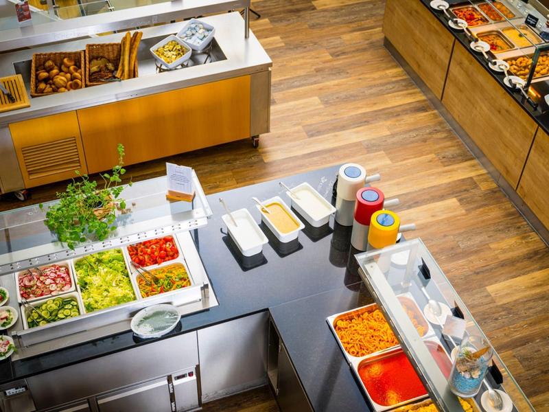 Buffetbereich mit frischen Salaten, Dressings und diversen Saucen in einem Restaurant.