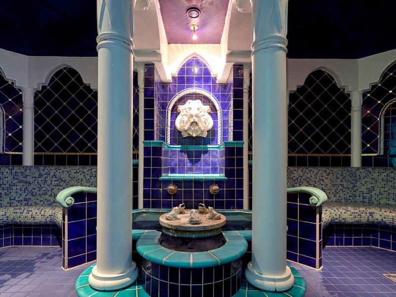 Luxuriöser Hammam mit blauen Fliesen, Säulen und zentralem Brunnen