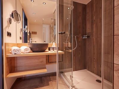 Modernes Badezimmer mit Holzakzenten, Glasdusche und Waschbecken in einem Hotelzimmer.
