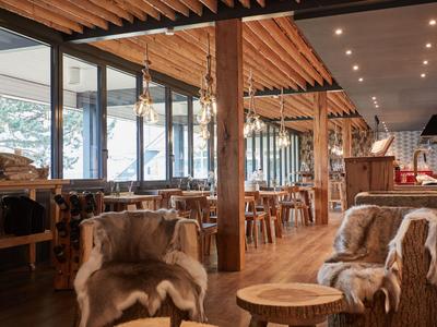 Holzinterieur eines gemütlichen Hotels mit Sitzgelegenheiten und großen Fenstern.