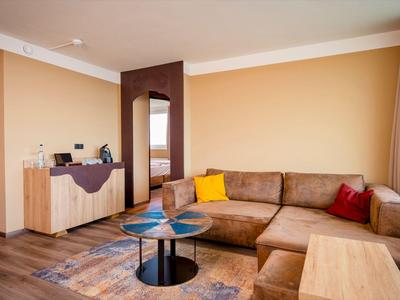 Gemütliche Hotellounge mit brauner Eckcouch, bunten Kissen und modernen Tischen.