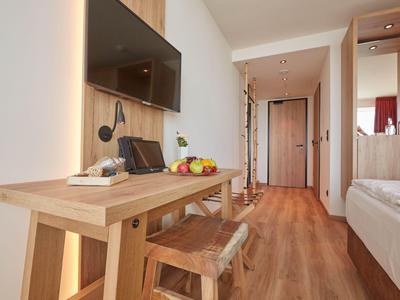 Moderner Hotelzimmer-Flur mit Holzmöbeln, TV und Blick zum Eingang.