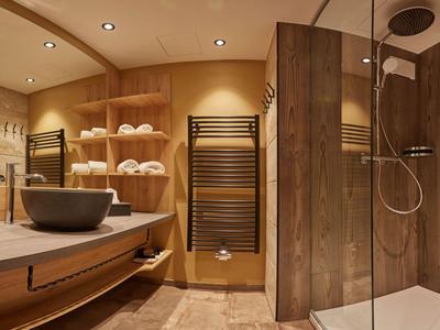 Moderner Hotelbadezimmer mit Holzakzenten, Glasdusche und Handtücher.