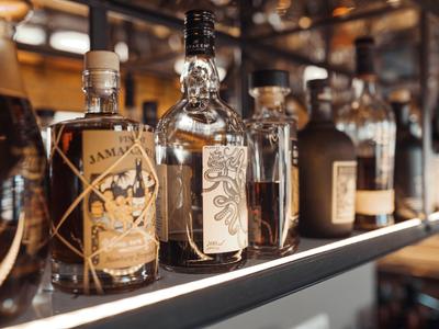 Verschiedene Whiskyflaschen stehen in einer warm beleuchteten Bar auf einem Regal.
