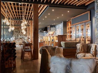 Cozy hotel bar with wooden ceiling, fireplace, and soft lighting.