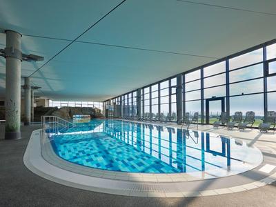 Moderní krytý bazén s velkými okny a lehátky v hotelu