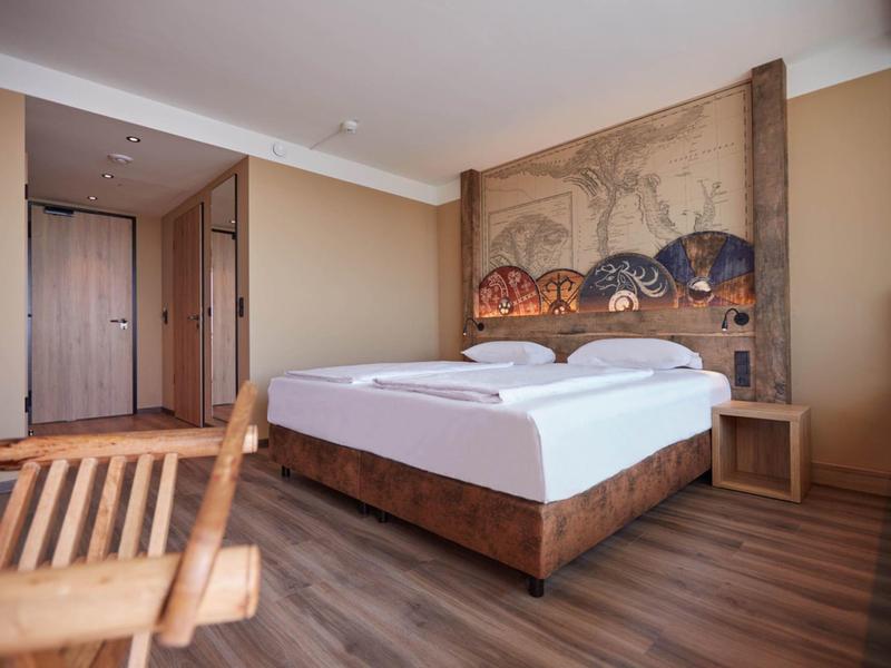 Ložnice s manželskou postelí, dřevěným nábytkem a teplým moderním designem.