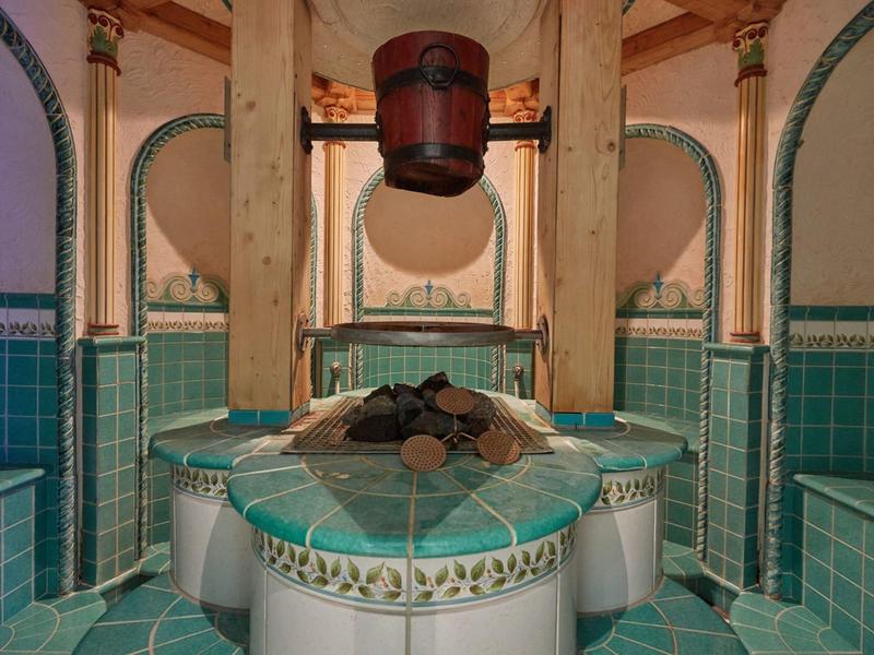 Tradiční turecké hammam s mramorovou platformou a dřevěnou nádobou zavěšenou na stropě.