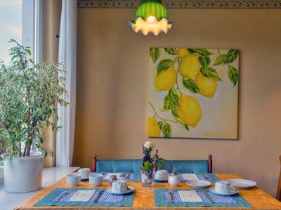 Gemütlicher Frühstücksbereich mit Zitrusbild an der Wand und dekorativem Pflanzenarrangement.