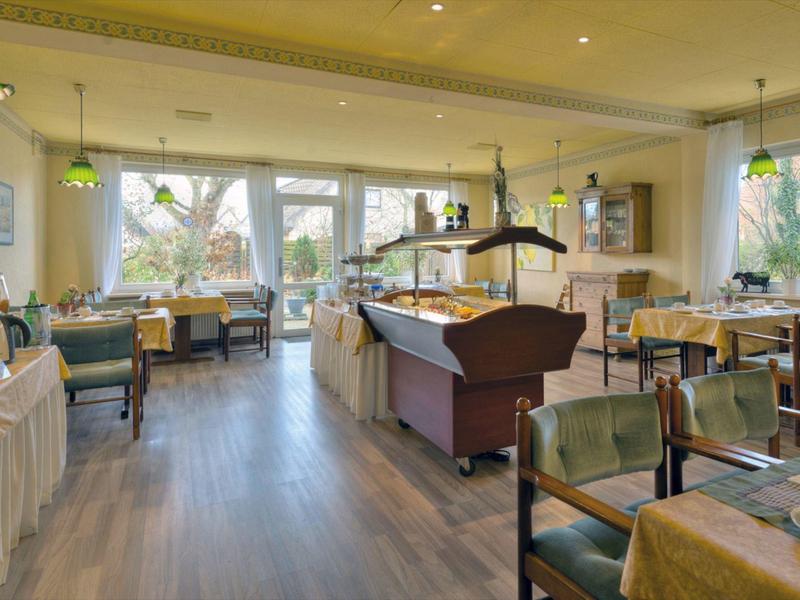 Brightly furnished hotel dining area with wooden floor and various seating options.