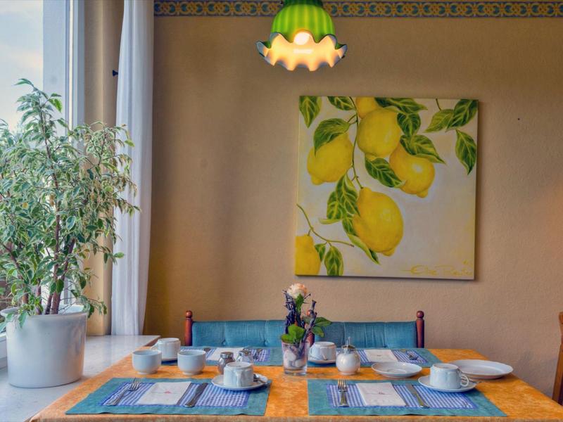 Cozy dining table with lemon painting and plants next to a large window.