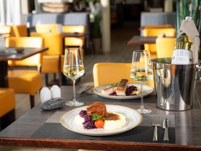 Elegantní restauranční stůl se dvěma sklenicemi na víno a servírovaným gurmánským pokrmem.