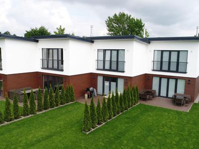Modernes, zweistöckiges Doppelhaus mit gepflegtem Garten und kleinen Hecken.