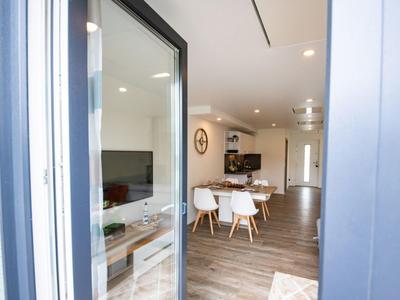 Moderner Essbereich mit weißen Stühlen und Holztisch neben der Küchentür in heller Wohnung.