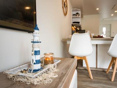 Tisch mit maritimem Dekor, Leuchtturmmodell und brennender Kerze in modernem Zimmer.