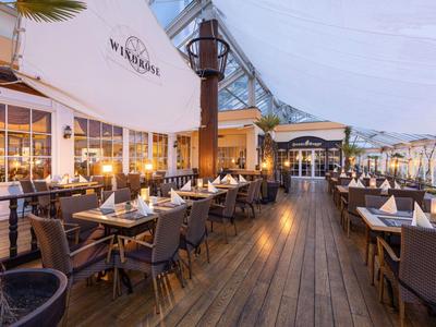 Elegancka restauracja na świeżym powietrzu z drewnianą podłogą i nakrytymi stołami o zmierzchu