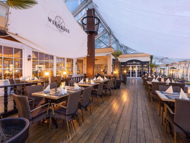 Elegancka restauracja na świeżym powietrzu z drewnianą podłogą i nakrytymi stołami o zmierzchu