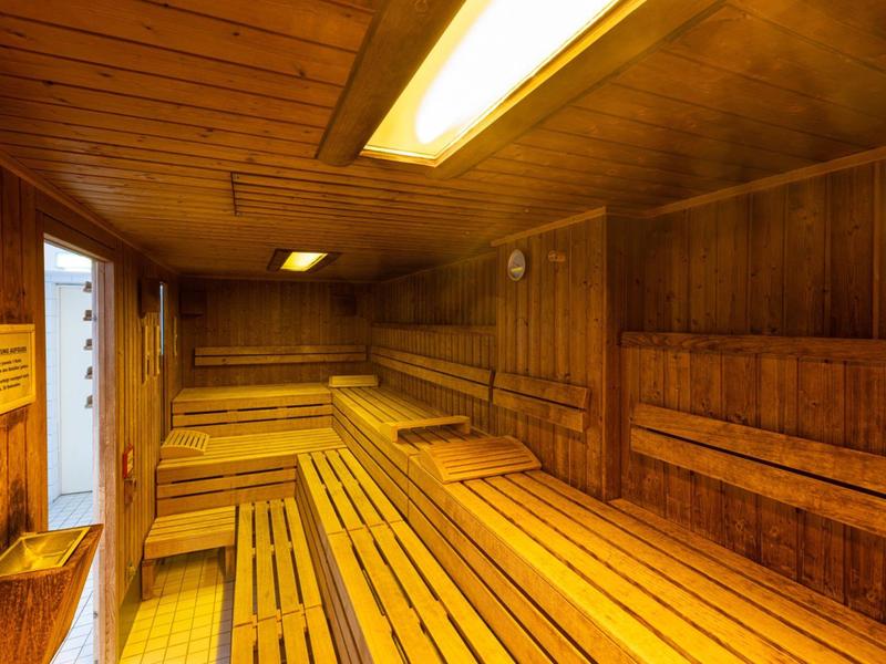 Wnętrze sauny fińskiej z drewnianymi panelami i ławkami do siedzenia.