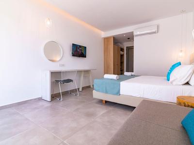 Modernes Hotelzimmer mit Doppelbett, Schreibtisch, Fernseher und minimalistischer Einrichtung.