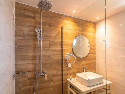 Modernes Badezimmer mit Holzoptik-Dusche, rundem Spiegel und weißem Waschbecken auf Holzregal.