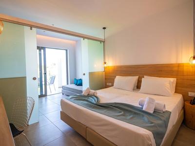 Helles, modernes Schlafzimmer mit Doppelbett, Holzakzenten und Zugang zu Balkon mit Sitzbereich.