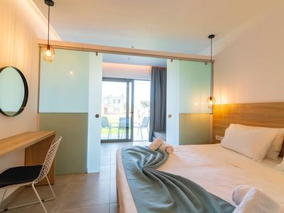 Modernes Schlafzimmer mit großem Bett, Holzdetails, Schreibtisch, Stuhl und Balkon mit Glasfront.