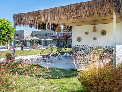 Überdachte Sitzecke mit Stühlen und Tisch im Garten eines Hotels bei Sonnenschein