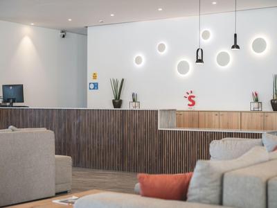 Moderner Hotellobby-Empfangsbereich mit dekorativer Wandbeleuchtung und bequemen Sofas.