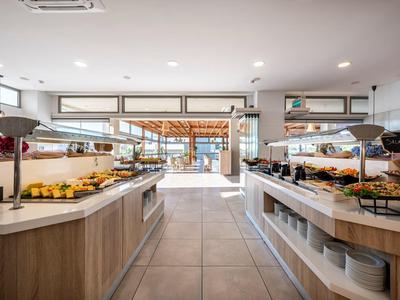 Buffetbereich mit frischem Obst und warmen Speisen in einem hellen, modernen Hotelrestaurant.
