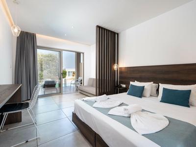 Modernes Hotelzimmer mit Doppelbett, Schreibtisch, Stuhl und Balkon mit Aussicht.