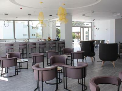 Moderner, heller Lounge-Bereich mit runden Stühlen, grauem Boden und großer Fensterfront.