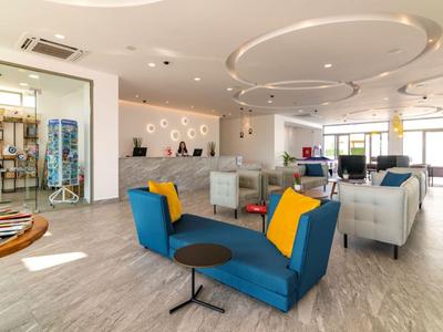 Heller Hotel-Lobbybereich mit modernen Möbeln, Teppichen und Empfangstresen.