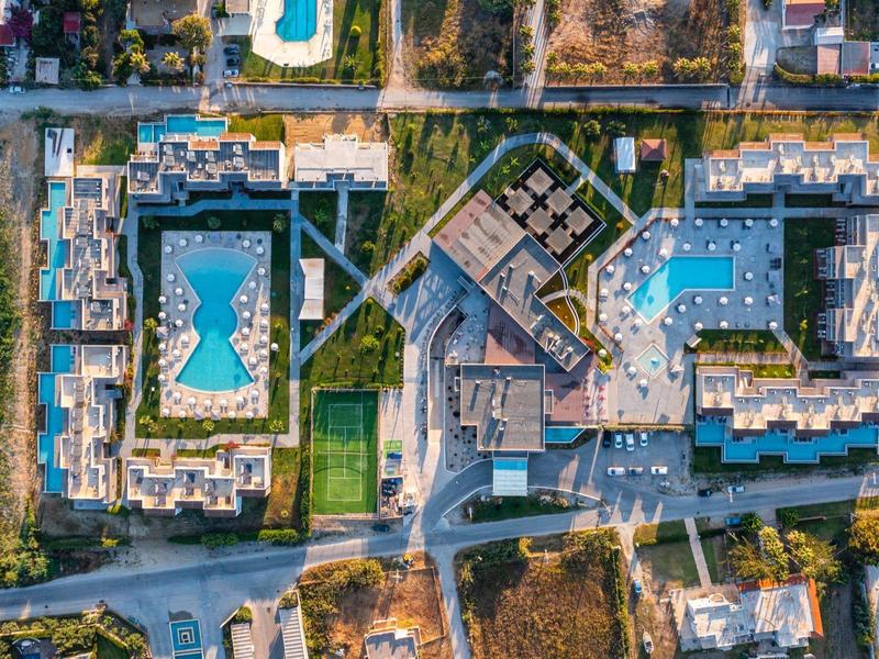 Aerial view of a large hotel with multiple swimming pools surrounded by trees