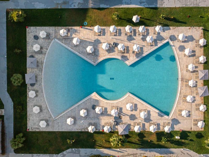 Outdoor pool in a unique fish shape with sun loungers at a hotel resort