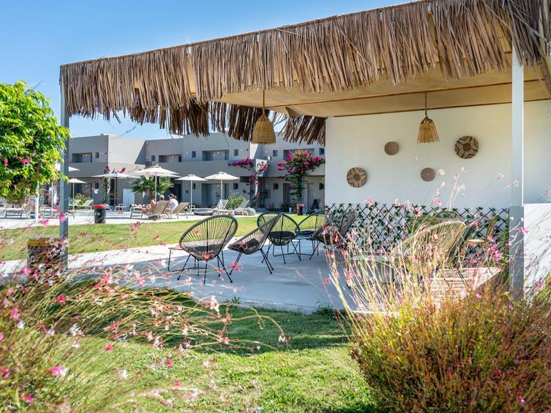 Covered seating area with chairs and table in a hotel garden under sunshine