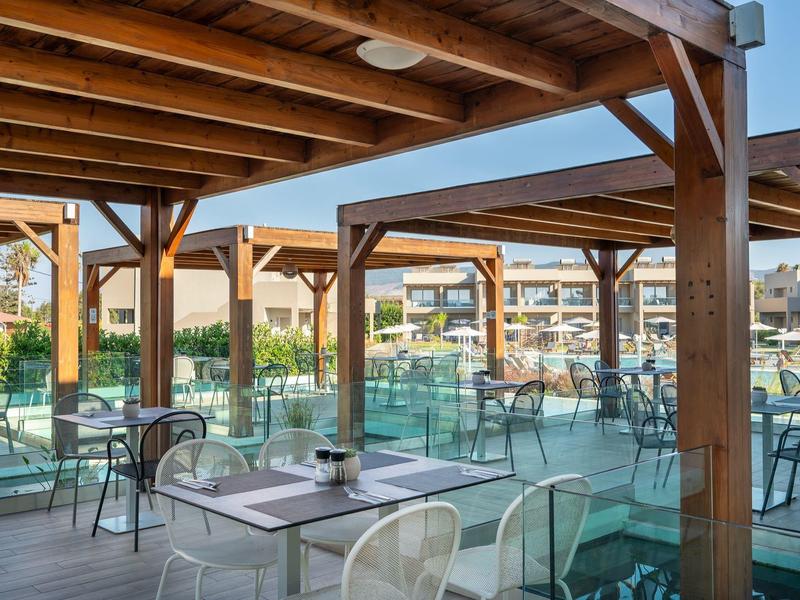 Covered terrace with glass railings and tables with chairs at a hotel or restaurant.