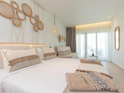 Licht ingerichte slaapkamer met tweepersoonsbed en natuurlijke wanddecoratie.