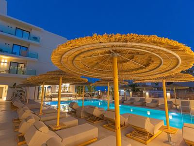 Poolbereich eines Hotels mit Liegestühlen und Strohmuscheln bei Sonnenuntergang