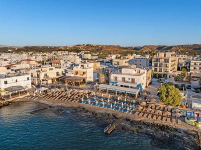 Uitzicht op een kustplaats met strand, parasols en gebouwen onder een heldere hemel.