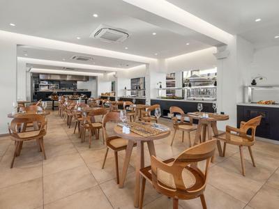 Modern, licht restaurant met bruine stoelen en houten tafels.