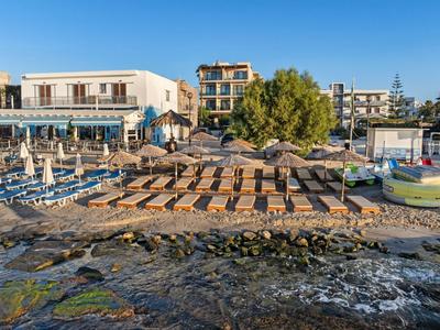 Een hotel met parasols en ligbedden op het strand bij helder weer.