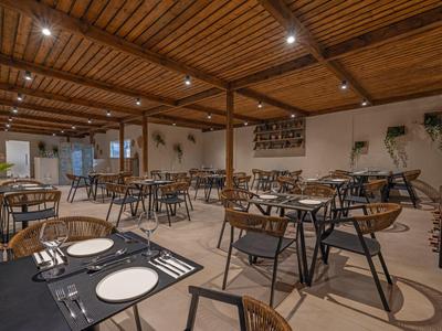 Moderne eetzaal met houten balkenplafond, elegant gedekte tafels en zacht daglicht.