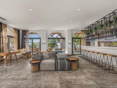 Heller Hotelbarbereich mit moderner Einrichtung, Bartresen und Sitzgelegenheiten mit Blick auf das Meer.